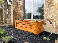 a wooden planter sitting in front of a window on top of a stone building