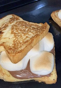 two pieces of toast with marshmallows and chocolate spread on them, sitting on top of each other