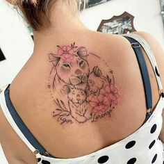 a woman with a tattoo on her shoulder and breast is holding a small baby lion