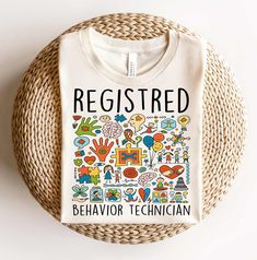 a white t - shirt with the words, register behavior technician on it sitting next to a wicker basket