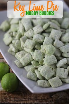 there is a white plate filled with muddy buddies next to limes on the table