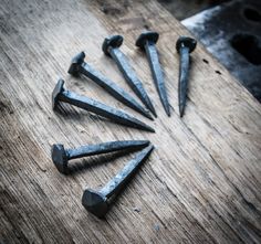 there are seven nails that have been placed on top of a wooden table with holes in it