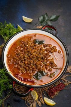 kadala curry in a bowl with garnishes and herbs on the side