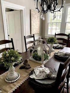 the dining room table is set with place settings and flowers in vases on it