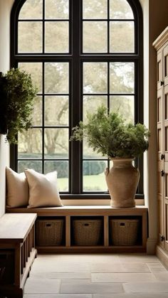 a large window sitting next to a wooden bench in front of a planter filled with potted plants