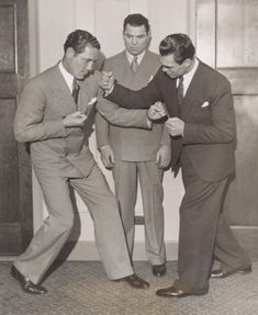 three men in suits and ties are punching each other's fists with their hands