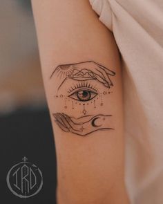 a woman's arm with two hands holding an eye tattoo on the left side of her arm