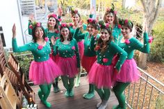 a group of young women dressed in green and pink posing for a photo on a deck