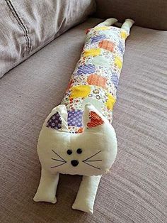 a cat pillow sitting on top of a couch next to a gray sofa cushion covered in colorful fabric