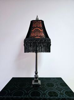 a lamp that is sitting on top of a table with a black cloth shade over it