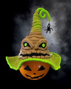 an orange pumpkin with a green hat on it's head and a spider hanging from the top