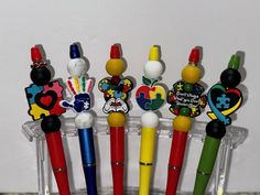 four different colored pens with mickey mouse magnets on them are in a clear holder