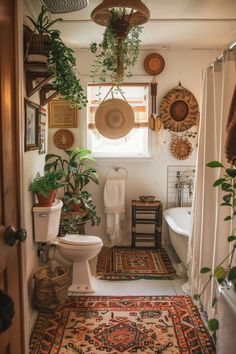 a bathroom with plants and rugs hanging from the ceiling in front of a window