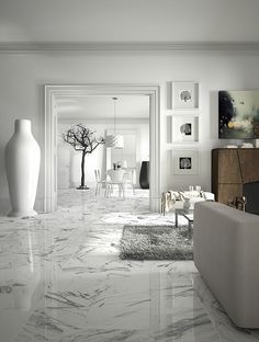 a living room with white walls and marble flooring is pictured in this image, there are two vases on the far wall