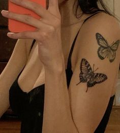 a woman with a butterfly tattoo on her arm holding a cell phone up to her face