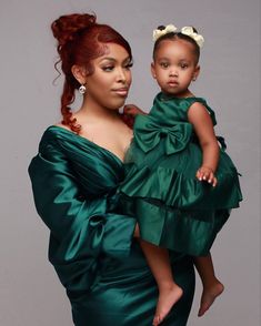 a woman in a green dress holding a baby