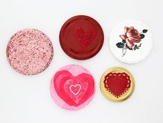 four buttons with hearts on them sitting next to each other in front of a white background