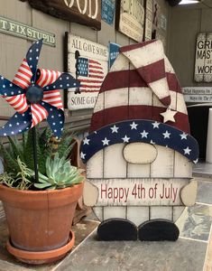 a potted plant sitting next to a wooden sign that says happy 4th of july