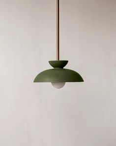 a green lamp hanging from a ceiling in a room with white walls and flooring