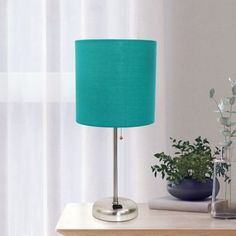 a green lamp sitting on top of a wooden table next to a potted plant