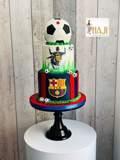 a multi - tiered cake with soccer themed icing on top is displayed in front of a wooden wall