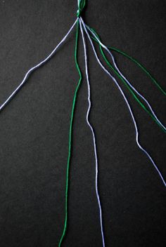 the green thread is being used to make an ornament with white and blue yarn