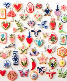 an assortment of ceramic ornaments are displayed on a white surface, including hearts, flowers, and other decorative objects