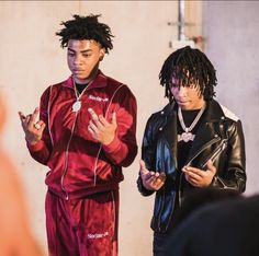 two young men standing next to each other in front of a wall wearing headphones