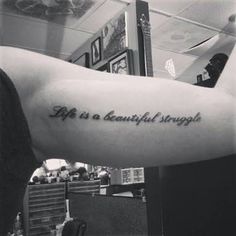 a person with a tattoo on their arm saying life is a beautiful struggle in black and white