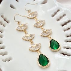 "Long boho bridal earrings with emerald green stones, long Art Deco earrings, gold statement earrings, drop earrings, fan earrings Dazzle at your wedding or party with these 1920s inspired long statement earrings with emerald green stones. These Art Deco earrings feature fan shaped sparkly crystals with emerald green teardrop stones at its ends. Complete your look with matching this matching fan necklace : https://www.etsy.com/YsmDesigns/listing/1309341599/ DIMENSION : ------------------- Earrin Emerald Green Dangle Earrings, Green Bohemian Earrings For Wedding, Bohemian Green Earrings For Wedding, Bohemian Green Chandelier Earrings For Wedding, Bohemian Green Bridal Earrings For Wedding, Green Dangle Chandelier Earrings For Weddings, Green Emerald Dangle Chandelier Earrings, Green Dangle Crystal Earrings For Wedding, Green Chandelier Drop Earrings For Wedding