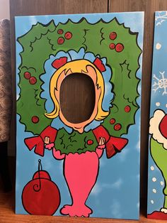 two paintings of cartoon characters on wooden boards, one is holding a christmas wreath and the other has a red ornament