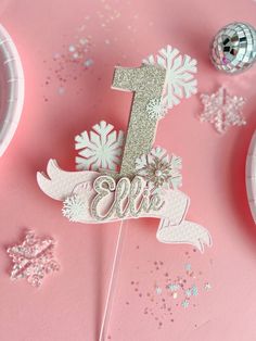 a cake topper with the number one on it and snowflakes around it