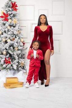 a woman and child standing in front of a christmas tree