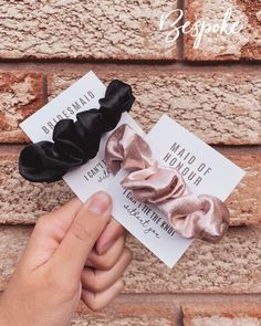 a hand holding a small black and pink hair bow