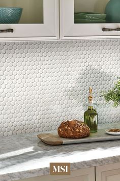 a kitchen counter with some bread and plants on it, next to two white cupboards