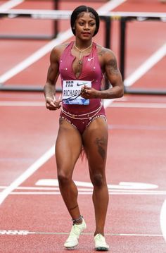 a woman running on a track in a pink top and red shorts with her hands behind her back