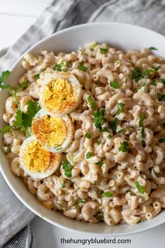 a bowl filled with macaroni and cheese topped with boiled hard boiled eggs on top