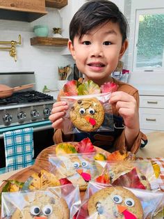 a little boy holding up some cookies and turkeys