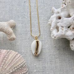 We love this fun and summery, beachy necklace. Answer the siren's song and get one for yourself or someone you love. Would make a great gift for the surfer or beach-lover in your life! A 14k gold electroplated cowrie shell dangles from a lustrous, high quality gold filled snake chain. The perfect summertime accessory! Chain length 16"✦ JEWELRY CARE ✦✧ Warm water and a soft cloth are the best thing you can do to maintain the beauty of your jewelry.✧ Jewelry polishing cloths work great and are non Gold Starfish Charm Necklace For Beach Season, Gold Necklace With Starfish Charm For Beach Season, Ocean-inspired Charm Necklace For Summer Beach, Summer Beach Ocean-inspired Charm Necklaces, Ocean-inspired Summer Beach Charm Necklace, Summer Beach Ocean-inspired Charm Necklace, Starfish Charm Strand Jewelry For Vacation, Starfish Charm Necklace For Beach Season Gift, Starfish Charm Jewelry For Vacation