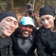 two men and a woman with face paint posing for a photo in front of a camera