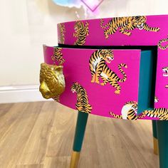 a close up of a pink table with tiger designs on the side and gold accents