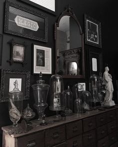 an old dresser is covered with antiques and framed pictures on the wall above it, along with other antique items