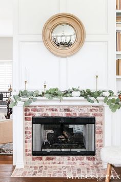 the fireplace is decorated with greenery and white pumpkins on it's mantle