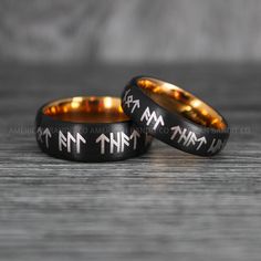 two black and gold wedding bands with roman numerals engraved on the inside of them