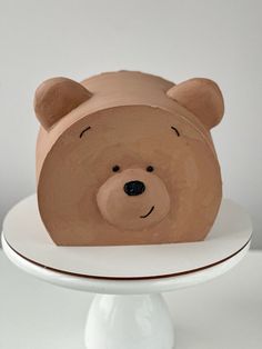 a brown teddy bear sitting on top of a white cake plate