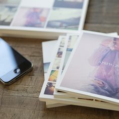 several polaroid photos are laying on the floor next to a cell phone