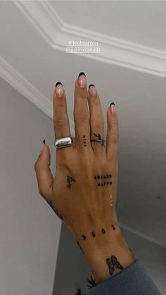 a person with tattoos on their fingers and hand holding something up to the ceiling in front of them