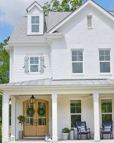 a large white house with two chairs on the front porch and one chair sitting outside