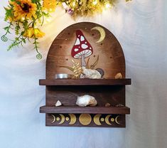 a wooden shelf with a mushroom on it next to flowers and other items in front of a white wall