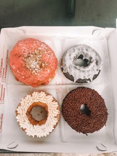 four different donuts in a box on a table